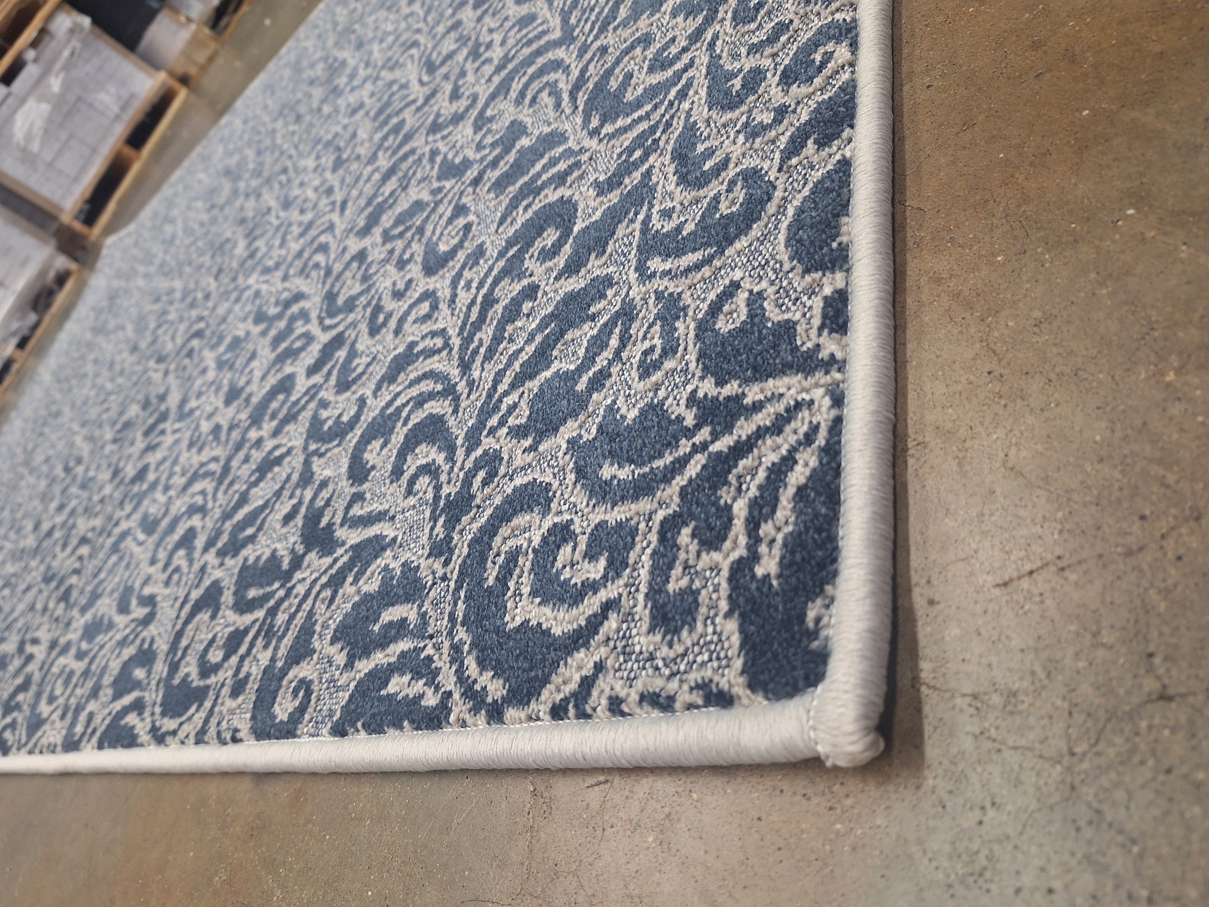 Custom blue damask area rug with cream serged edge made at James Flooring Springfield